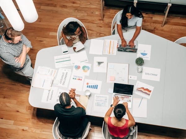 Un grupo diverso que trabaja en estrategias de marketing con gráficos y ordenadores portátiles en un entorno de oficina.