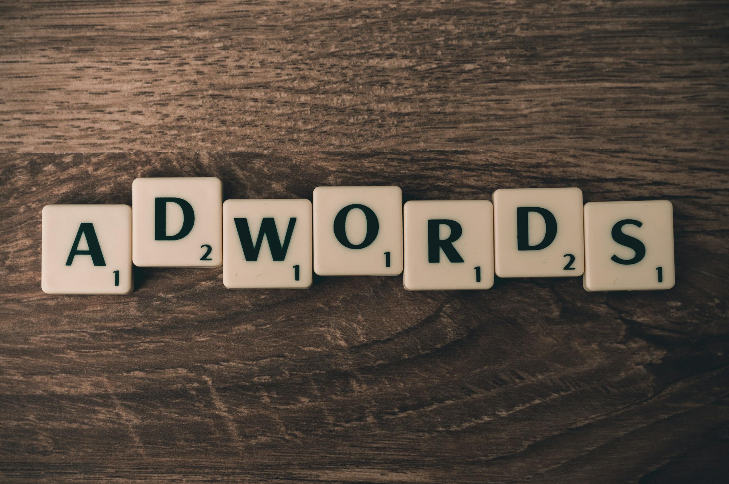 Las fichas de Scrabble deletrean "AdWords" sobre una superficie de madera, simbolizando conceptos de marketing digital.